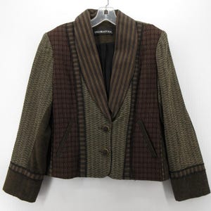 May include: A multi-textured blazer in shades of brown, olive green, and black. The jacket features a notched lapel, two-button closure, and two front pockets. The brand name "COLORATURA" is visible on the label.