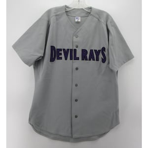May include: Gray baseball jersey with the text "DEVIL RAYS" in navy blue across the chest. The jersey has short sleeves, a button-up front, and a V-neck collar. The jersey is hanging on a hanger.