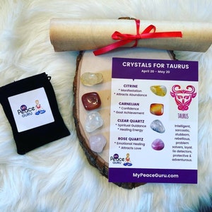 May include: A set of five crystals for Taurus, a purple card with the text "Crystals for Taurus" and "April 20 - May 20", a brown scroll tied with a red ribbon, and a black pouch with the text "My Peace Guru". The crystals are citrine, carnelian, clear quartz, and rose quartz.