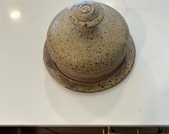 Plato de queso de cerámica con tapa hecho a mano (u otro) y tarro de mermelada, miel o salsa.