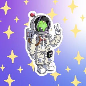 May include: A sticker featuring a cartoon alien in a white spacesuit with a red antenna, giving a peace sign. The alien has a green head and is wearing a helmet. The background is a gradient of purple and blue with yellow star shapes.
