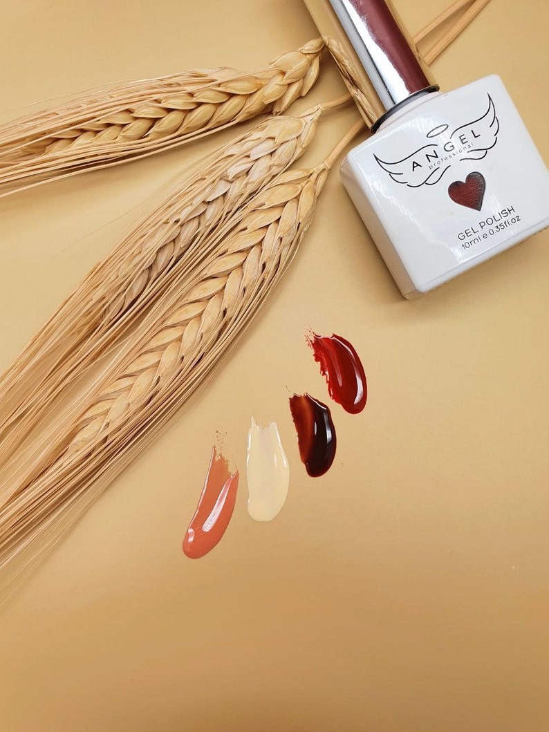 May include: A clear glass bottle of gel polish with a silver cap. The bottle is labeled "ANGEL Professional" and "GEL POLISH 10ml e 0.35fl oz". There are four small swatches of nail polish on a beige background: red, dark brown, light brown, and peach.