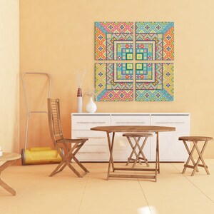 Puede incluir: Un conjunto de cuatro piezas de arte de pared de lienzo con patrones geom&eacute;tricos coloridos que cuelgan de una pared de color naranja claro sobre una c&oacute;moda blanca con una mesa y sillas de madera delante.