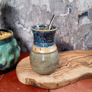 Può includere: Una tazza di ceramica bianca con manico nero e la scritta "But First, Coffee" in grassetto nero. La tazza è posta su uno sfondo sfocato, che suggerisce un'atmosfera accogliente.