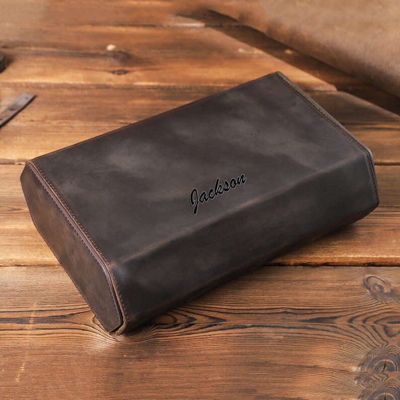 May include: A brown leather case with the name "Jackson" embossed on the top.