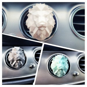 Könnte beinhalten: Eine Collage von drei Auto-Luftauslass-Diffusoren in Form eines Löwenkopfes. Die Löwenköpfe sind weiß, grau und hellblau. Die Diffusoren sind in die Lüftungsschlitze des Autos eingesetzt, die silberfarben sind.