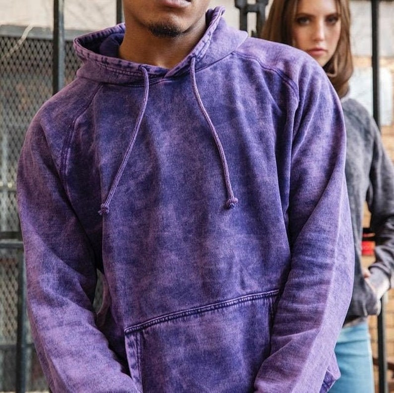May include: A purple hooded sweatshirt with a distressed, faded look. The sweatshirt has a drawstring hood and a kangaroo pocket.
