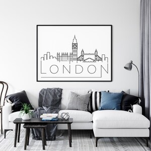 May include: Black and white line art print of the London skyline featuring Big Ben, the Houses of Parliament, and Tower Bridge. The print is framed and hanging on a white wall above a white couch with black and white throw pillows.