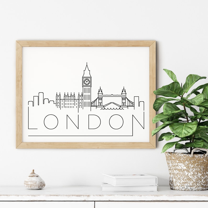 May include: A black and white line art print of the London skyline featuring Big Ben, the Houses of Parliament, and Tower Bridge. The print is framed in a light wood frame and the word "LONDON" is written below the skyline.