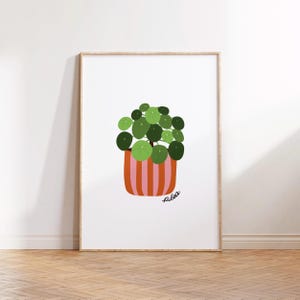 May include: A digital illustration of a Pilea plant in a pink and orange striped pot. The plant has round, green leaves and the pot has the word "Pilea" written on it.