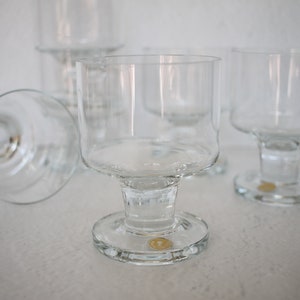 May include: Four clear glass goblets with a wide bowl and a short stem. The goblets have a round base.