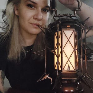 Könnte beinhalten: Eine große, verzierte Metall-Laterne mit einem spitzen, stacheligen Design. Die Laterne hat eine klare Glasscheibe und ein warmes, leuchtendes Licht im Inneren.