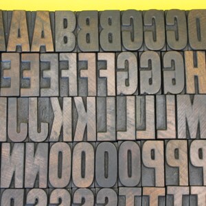 May include: A collection of wooden letter blocks in various sizes, arranged in alphabetical order. The blocks are made of dark wood with a natural grain pattern.