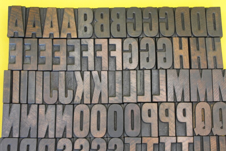 May include: A collection of wooden letter blocks in various sizes, arranged in alphabetical order. The blocks are made of dark wood with a natural grain pattern.