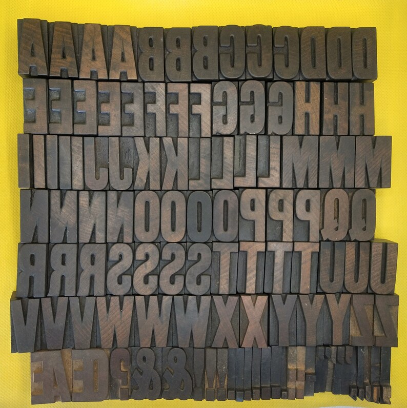 May include: A close-up of a set of wooden letterpress blocks, each with a different letter of the alphabet. The blocks are arranged in rows, with the letters A through Z.