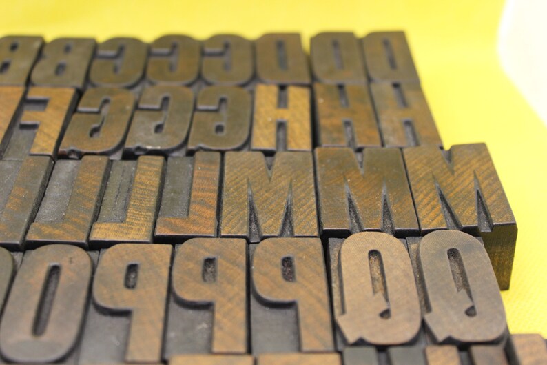 May include: A collection of wooden letter blocks in various sizes, including the letters G, C, H, L, M, P, and Q. The blocks are arranged in a staggered pattern, with the letters facing forward.