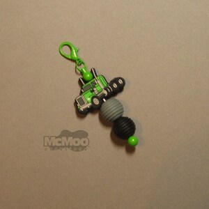 May include: Green truck charm with black and gray beads and a green clip. The charm says "McMoo Creations" on the bottom.