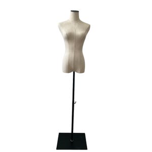 May include: A beige fabric dress form with a black metal stand and base. The dress form is shaped like a torso and has a neck. The stand is adjustable and the base is square.