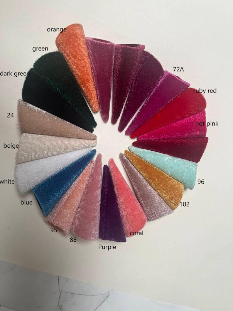 K&ouml;nnte beinhalten: Eine Farbkarte mit 12 Samtstoffproben in verschiedenen Farben, darunter Orange, Dunkelgr&uuml;n, Gr&uuml;n, Beige, Wei&szlig;, Blau, Koralle, Lila, Pink, Rubinrot und zwei Rosat&ouml;ne. Die Proben sind kreisf&ouml;rmig angeordnet und mit Zahlen beschriftet.