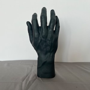 Op de afbeelding: Een zwart handbeeld met gedetailleerde vinger- en adertexturen. De hand is omhoog geheven met licht gespreide vingers.