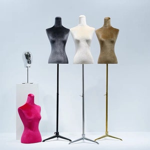 May include: Four adjustable mannequins with velvet-covered torsos in gray, white, brown, and pink. The mannequins are on stands with adjustable heights. The stands have a tripod base.
