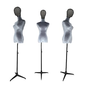 May include: Three grey dress forms with black metal stands. The dress forms have a textured fabric body and a wire mesh head. The stands have a four-pronged base and an adjustable height. The dress forms are designed for displaying clothing.