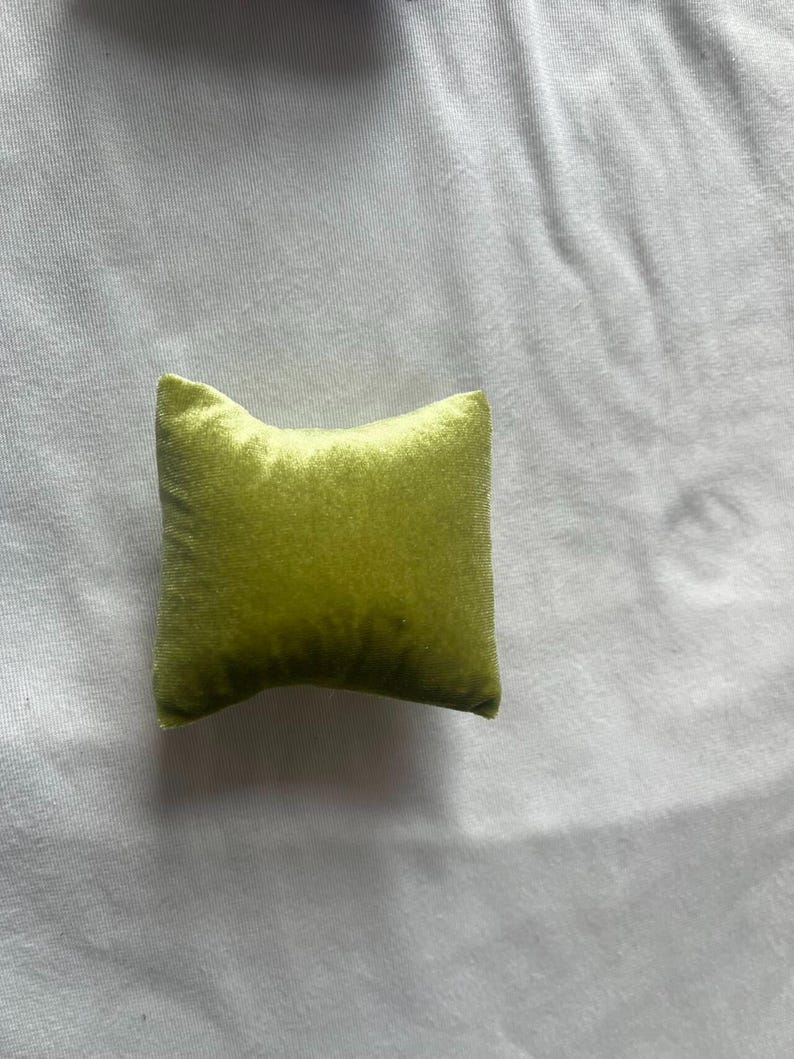K&ouml;nnte beinhalten: Ein kleines, quadratisches Kissen mit weicher, samtiger Textur. Das Kissen ist in einem leuchtenden Limettengr&uuml;n.