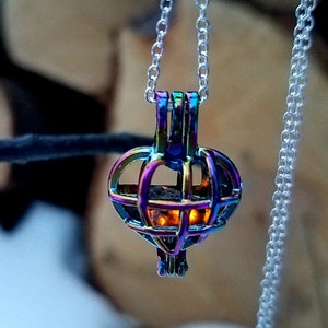 May include: A silver chain necklace with a pendant. The pendant is a cage-like design with a rainbow iridescent finish, showcasing hues of purple, blue, and gold. The pendant is suspended from a delicate silver chain.
