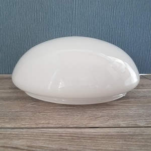 May include: A white, opaque glass lampshade with a rounded, dome-like shape. The shade has a smooth, glossy surface and a slightly flared base. It is designed to diffuse light and is suitable for various lighting fixtures.