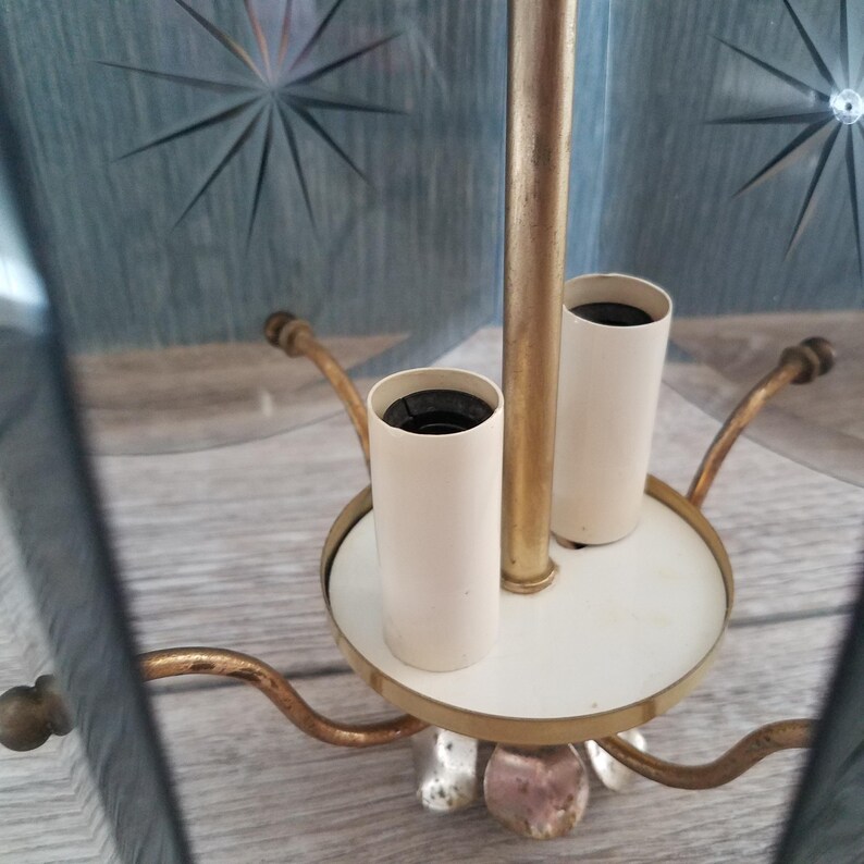 May include: Vintage brass and glass chandelier with starburst etched glass panels. The chandelier features a white base with two light sockets and decorative arms. The glass panels are a light blue color.