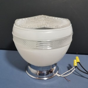 May include: A vintage white and chrome ceiling light fixture. The light has a rounded, globe-like shape with a clear, textured glass top and a decorative band. The base is chrome, and the fixture has exposed wiring.