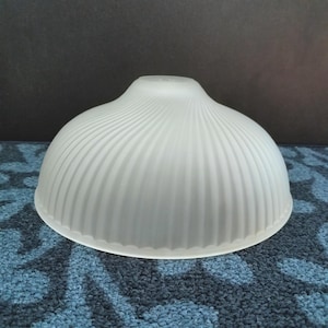 May include: A white, frosted glass lampshade with a ribbed, dome-like design. The shade has a rounded top and a flared bottom, suitable for a ceiling light fixture. The shade is made of a translucent material.