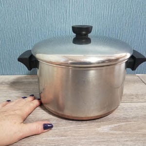 May include: A white ceramic mug with a black handle and the text "But First, Coffee" in a black, handwritten-style font. The mug is on a white surface.