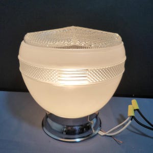 May include: A vintage-style, frosted glass light fixture with a chrome base. The fixture has a rounded, bulbous shape with a textured glass top and a decorative band. Exposed wires with yellow wire connectors are visible.