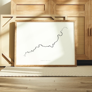 May include: A minimalist black and white print of the Ohio River. The print is framed in a light brown wood frame and is displayed on a light brown wooden floor.