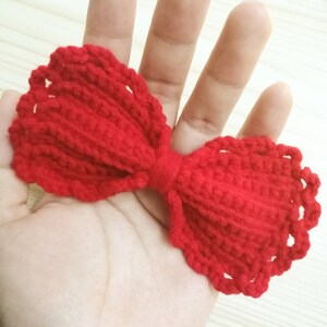 Puede incluir: Un lazo de crochet rojo con borde festoneado.