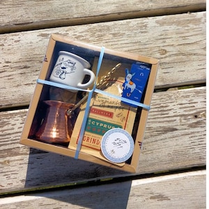 Op de afbeelding: Een cadeauset voor het maken van Griekse koffie. De set bevat een koperen koffiepot, een klein wit kopje, een koffielepel, een zakje Cyprus koffie en een blauw-witte sticker met een Grieks sleutelmotief.