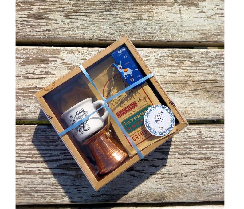 May include: A gift box set for making Greek coffee. The set includes a small white ceramic mug with a donkey design, a copper cezve, and a bag of Cyprus coffee.