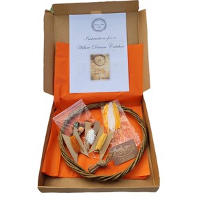 May include: A brown cardboard box with orange tissue paper inside. The box contains a willow dream catcher kit with a willow hoop, feathers, yarn, beads, and instructions. The box also includes a thank you card.