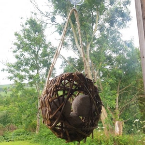 Peut inclure: Un nid d'oiseau en osier brun avec trois boules d'argile brunes &agrave; l'int&eacute;rieur, suspendu &agrave; une fen&ecirc;tre avec une ventouse.