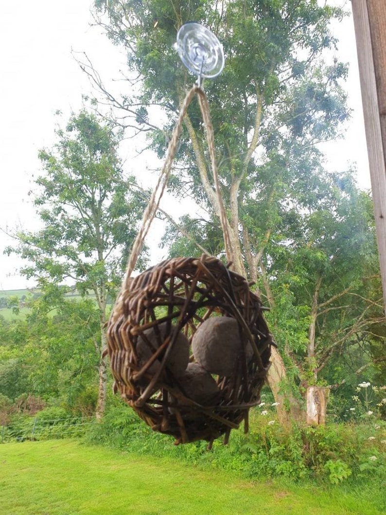 Peut inclure: Un nid d'oiseau en osier brun avec trois boules d'argile brunes &agrave; l'int&eacute;rieur, suspendu &agrave; une fen&ecirc;tre avec une ventouse.