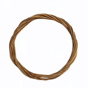 Puede incluir: Una corona de ramas marrones con un acabado de purpurina dorada. La corona es circular y tiene un di&aacute;metro de aproximadamente 30 cm.