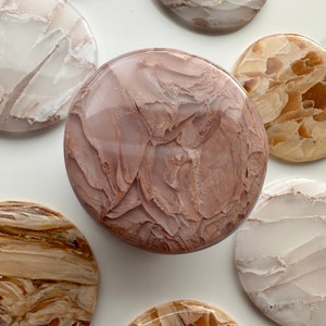 May include: A collection of round agate coasters in various shades of brown, white, and pink. The coasters have a natural, marbled pattern.