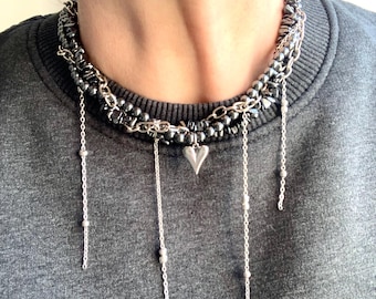 Puede incluir: Un collar de cuentas de plata y negro en capas con un dije de corazón y cadenas colgantes.