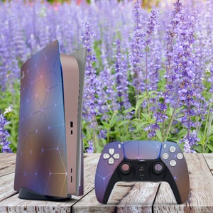 May include: A purple and blue PlayStation 5 console with a geometric pattern and a matching purple and blue controller. The console and controller are sitting on a wooden surface.