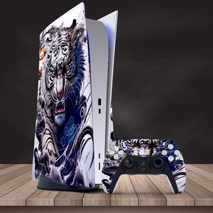 Könnte beinhalten: Eine weiße und blaue PlayStation 5 Konsole mit einem weißen Tiger-Design. Die Konsole steht auf einer Holzoberfläche. Ein passender weißer und blauer PlayStation 5 Controller befindet sich vor der Konsole.