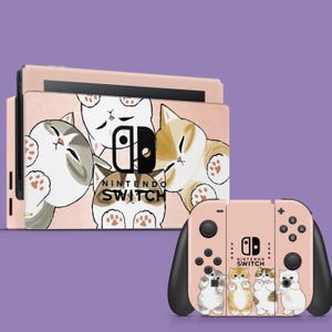 May include: A pink Nintendo Switch console and controller skin featuring a playful cat design. The console skin has a group of cats, and the controller has four cats. The Nintendo Switch logo is visible.