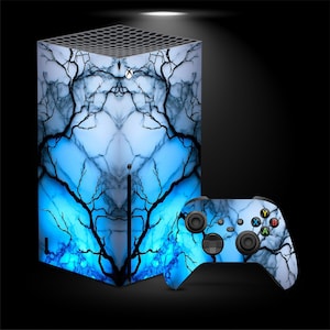 以下が含まれることがあります： 青と白の大理石模様と黒い木の枝のアクセントが特徴のゲーム機とコントローラーのセット。コンソールは長方形のタワーで、コントローラーは色付きのボタンが付いたお揃いのデザインです。