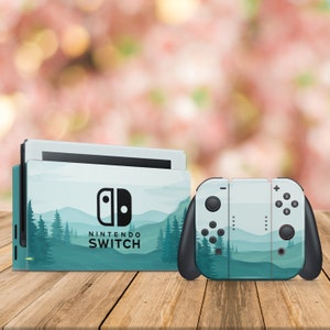 Puede incluir: Una consola y un mando de Nintendo Switch de color verde y azul con un diseño de paisaje de montaña y bosque. La consola tiene el texto "NINTENDO SWITCH" en la parte delantera.