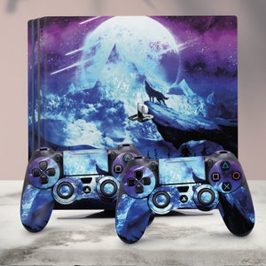 May include: Two black PlayStation 4 controllers with a blue and purple galaxy design featuring a wolf howling at the moon. The controllers are on a white surface.